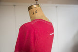 Back view of a watermelon red scoop neck t-shirt with white contrast stitch detail.