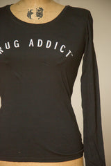 Form-fitting women's long sleeve t-shirt in black with arched Rug Addict text.