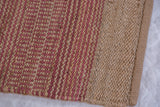 Detailed view of handmade Razz jute rug with natural and reddish-pink stripes.