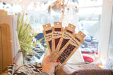 Hand holding five BookRug bookmarks, featuring diverse traditional and geometric rug patterns.
