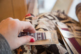 Hand holding a Jade Fars Pictorial bookmark featuring diamond patterns and its MouseRug tag.