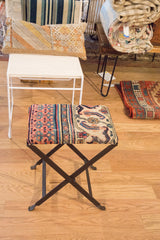 Antique Persian Khorassan rug fragment footstool featuring coral, teal, cream curvilinear motifs on a dark base.