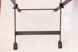 Reclaimed industrial dark metal folding base of the footstool.