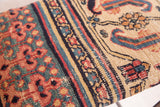 Close-up of antique Persian Khorassan Doroksh rug fragment's coral, teal, and beige floral pattern.
