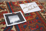 The textured surface of the antique rug cork board in use with a pinned photo and note.