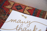 A gold arrow pin secures a card, highlighting the woven texture of the antique rug cork board.