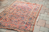 Pinkish red field, blue Herati pattern, and unique scrolling border of an antique Persian tribal rug.