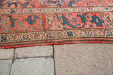 Shabby antique Persian tribal rug detail: scrolling arabesque border with worn pinkish-red field.