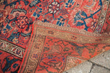 Faded red and blue Herati design on antique Persian tribal rug corner, revealing dense plain weave.