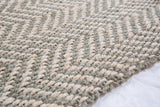 Chunky hand-woven jute rug in sage green and natural beige chevron pattern.