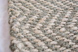 Tactile hand-woven pure jute rug featuring interwoven sage green and undyed natural fibers.