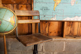 Adjustable black cast iron base and aged wooden seat detail of an antique school chair.