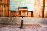 Back of antique industrial school chair, showcasing hand-painted flowers on wood.
