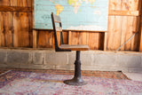 Side profile of antique wood and iron school chair, showing painted flowers and adjustable base.