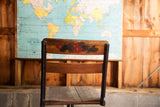Antique school chair's wooden backrest with charming hand-painted red floral motif.