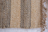 Textured close-up of Slate jute rug, featuring natural and gray vertical stripes with fringe.