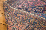 Distressed Malayer rug's secure side, intricate navy, blush, and mustard geometric pattern.