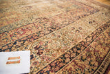 Detailed view of the antique Kermanshah carpet's milfleur design in red, navy, and ivory tones.