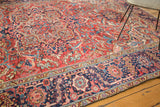 Vintage Heriz carpet with low pile, showing madder red field and navy blue border.