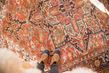 Vintage Heriz carpet featuring rich red, navy, and seaglass geometric patterns in sunlight.
