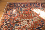 Vintage Heriz carpet corner with red, navy, and seaglass geometric patterns, aged fringe.