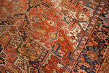 Vintage Heriz carpet detail: geometric pattern with rich red field and a navy border. Visible wear.