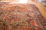 Ornate navy border of vintage Heriz rug, highlighting rich red field and delicate side tatter.