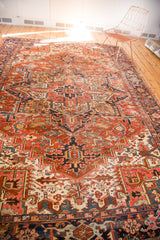 Vintage Heriz rug's geometric red and blue patterns, showing areas of wear.