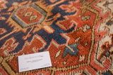 Rich red, navy, and seaglass geometric patterns on a vintage Heriz rug's textured pile.
