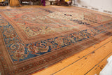 Intricate blue border and patinated copper-bronze field of an antique Persian Farahan rug.