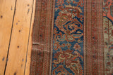 Frayed edge of an antique Farahan carpet, revealing intricate jewel-toned botanical patterns.