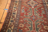 Angled view of the tattered side and geometric border on a vintage Turkish rug.