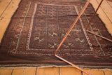Vintage Belouch rug's allover diamond geometric pattern in deep browns, dull navy, and ivory with aged edges.