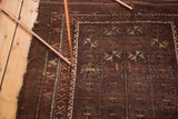 Vintage Belouch rug, geometric starburst pattern in rich brown, dull navy, and ivory, with aged side.