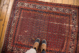 Vintage Hamadan rug, abrashed red boteh design, navy blue borders, visible patches and fraying.