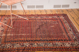 Abrashed red field with allover repeating boteh design on vintage Hamadan rug, visible wear.