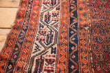 Vintage Hamadan rug's frayed side edge, revealing geometric patterns in navy, ivory, and red.