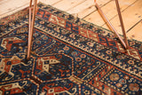 Indigo blue, brick red geometric motifs and tattered edge of vintage Shirvan rug.