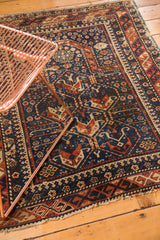 Shirvan rug with tattered bottom edge, featuring indigo, brick red, and ivory geometric patterns.