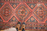 Vintage North West rug in faded red with geometric pattern and distressed texture, underfoot.
