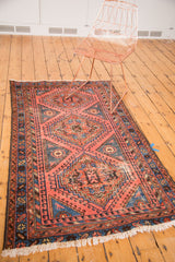Vintage North West rug corner with faded red and blue geometric border and tattered fringe.