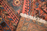 Corner of vintage North West rug displaying geometric patterns, ivory fringe, and hand-knotted back.