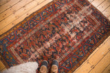 Malayer rug's intricate blue and red herati pattern, highlighting worn side with exposed foundation.