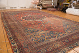 Antique Bijar carpet corner with storied texture, rich red and navy floral motifs.