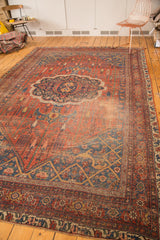 Antique Bijar rug's bottom corner, featuring brick red field, navy blue borders, and storied patina.