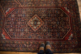 Engelas rug corner, brick red border, and navy blue field with intricate Herati pattern.