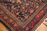 Vintage Mahal rug corner with intricate dark navy field, cherry red border, and ivory fringe.