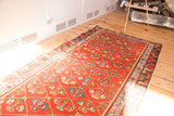 Antique Hamadan runner with cherry red field and diamond lattice containing rainbow-like floral motifs.