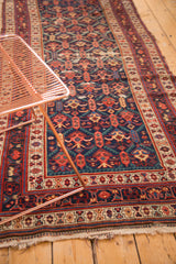 Antique Caucasian runner displays geometric pomegranate and serrated leaf motifs in navy, red, and teal.
