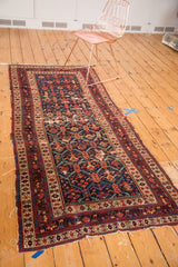 Antique Caucasian runner's navy field, detailed blossoming pomegranate and serrated leaf motifs, visible wear.